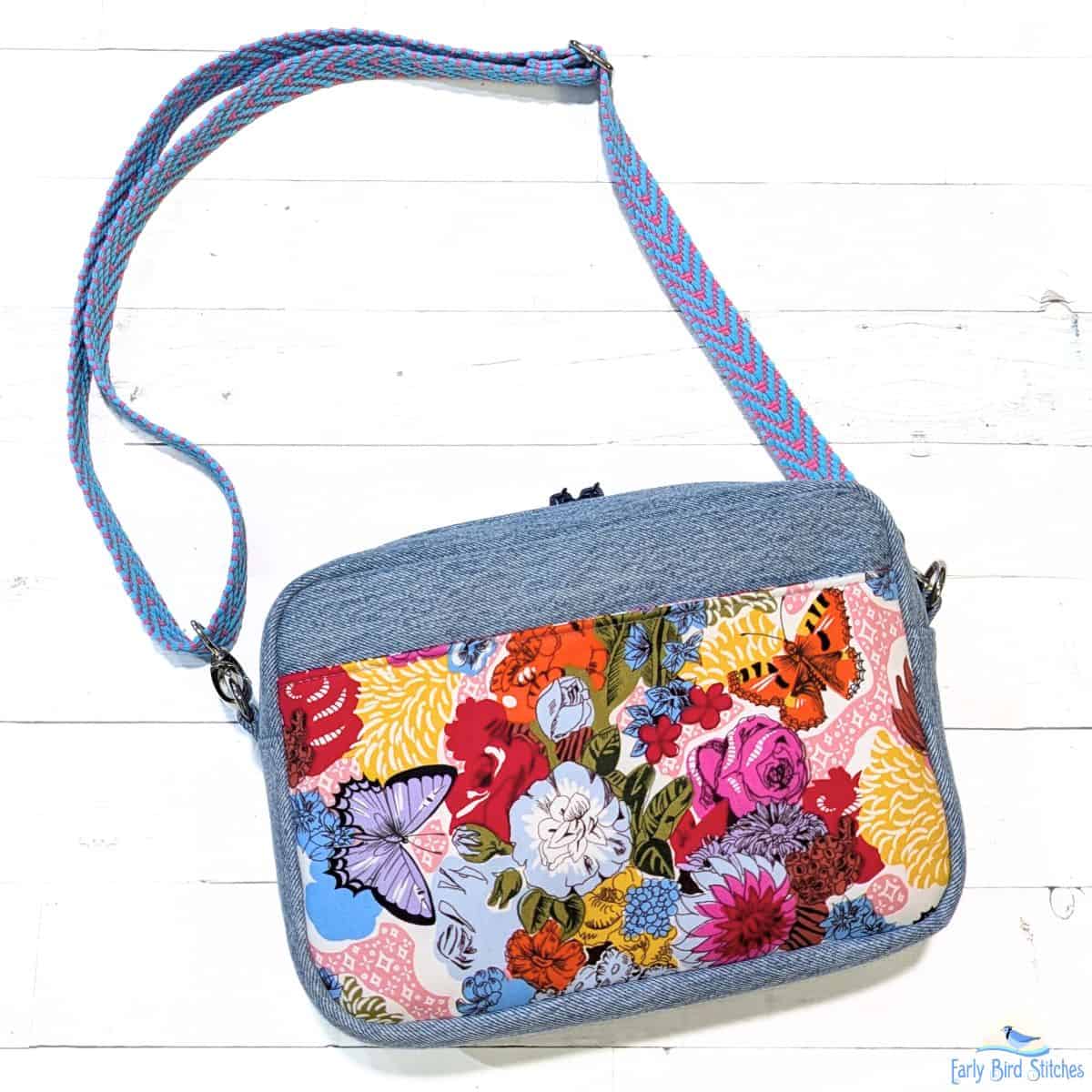 Handmade crossbody bag with denim exterior, front pocket panel, and woven adjustable strap
