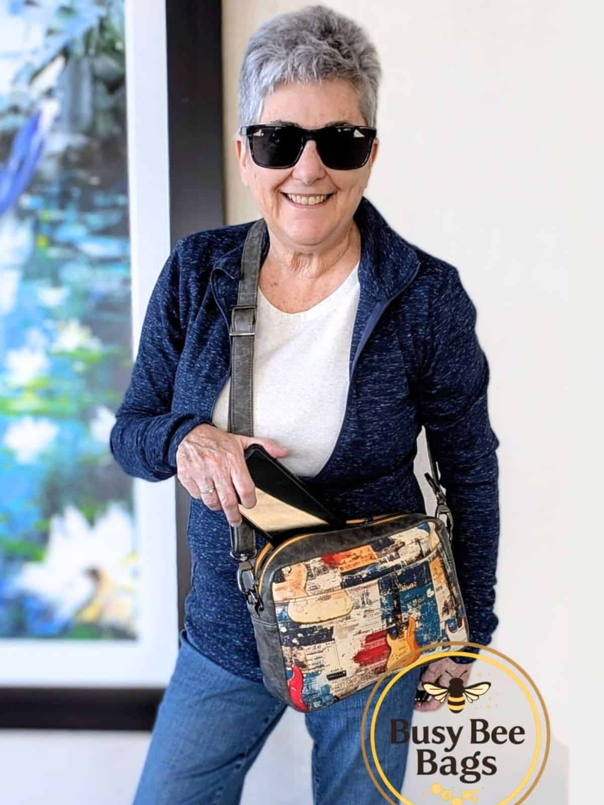 Handmade crossbody bag worn crossbody, zippered top opening, front slip pocket, and adjustable strap in use.