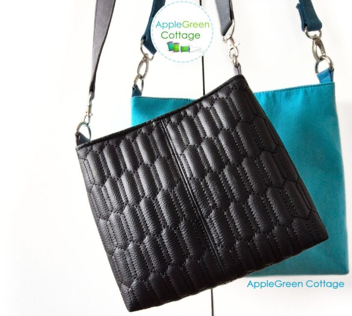 A beautiful handmade black faux leather bag hanging on a sleek faux leather shoulder strap.