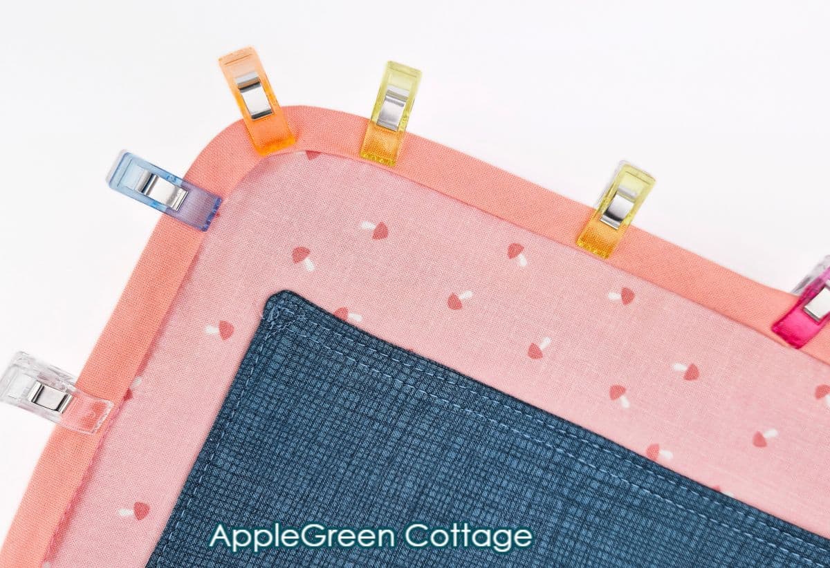 Bias tape clipped around curved fabric edge, ready for topstitching on bag or quilt.