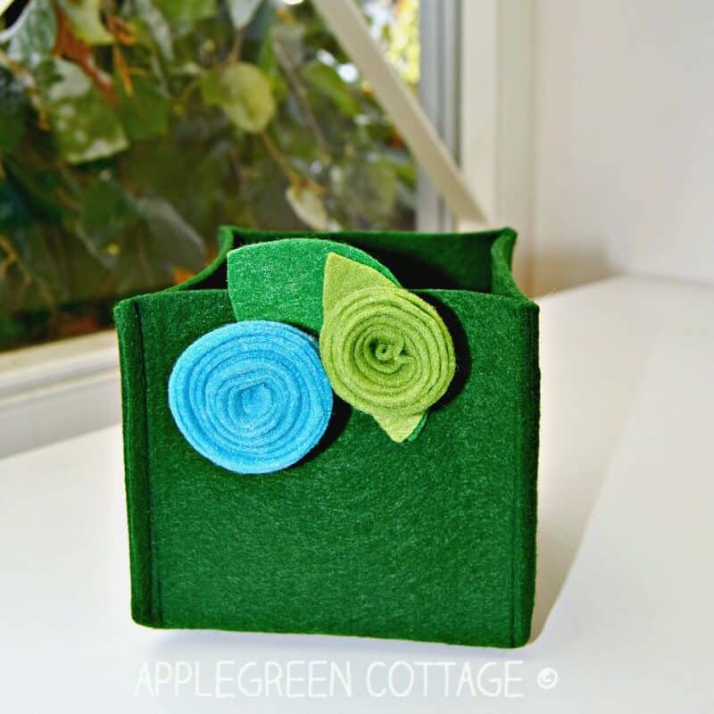 A finished green felt box with floral decoration on a tabletop.