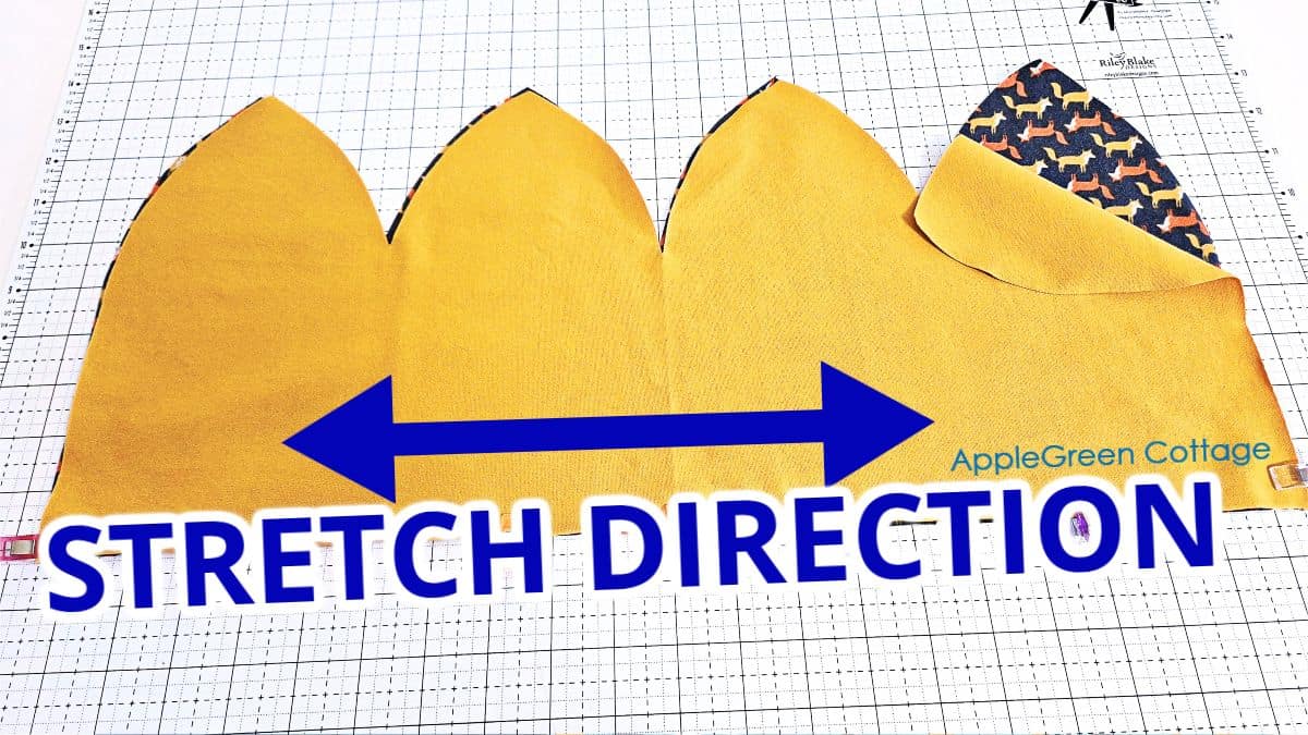 Two pieces of cotton jersey cut for a beanie hat, with markings showing the stretch direction.