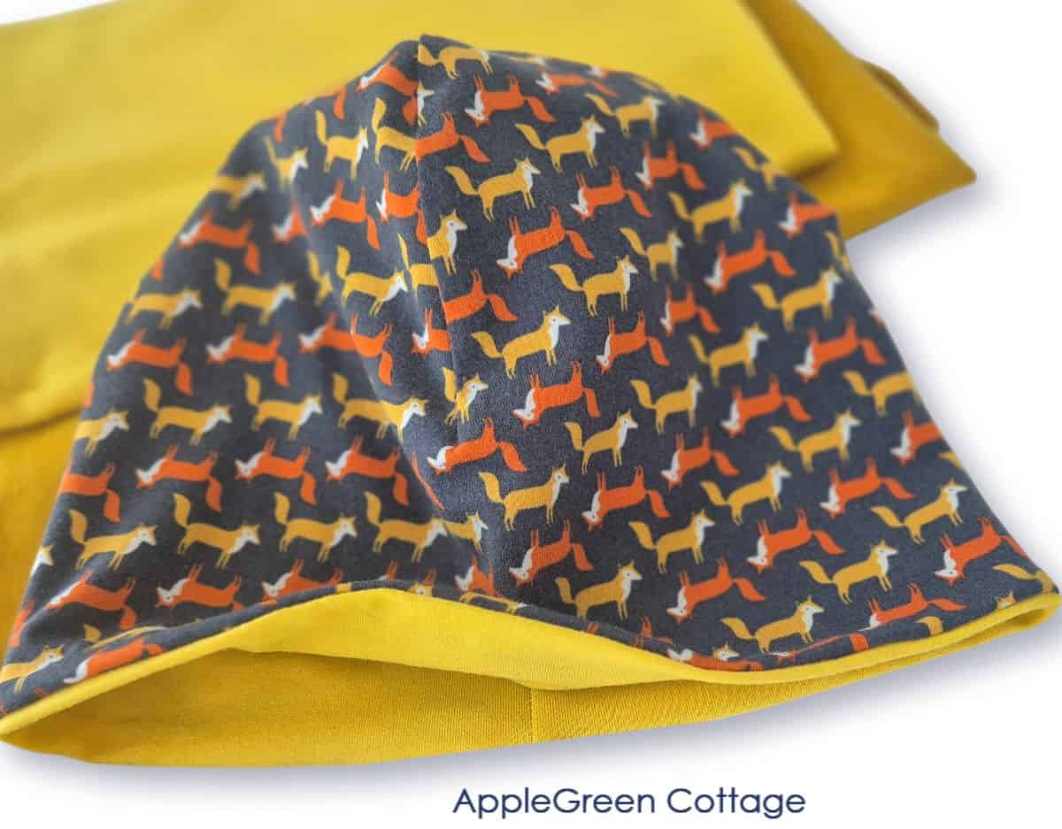 Reversible lined beanie hat in fox print knit with mustard lining, finished sewing project close-up.