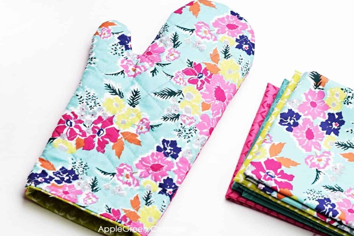 a finished quilted fabric oven mitt on a flat surface, featuring a beautiful floral print