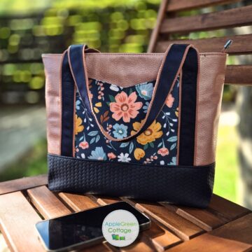 Finished AVELA tote bag with floral front pocket, navy handles, and structured bottom.