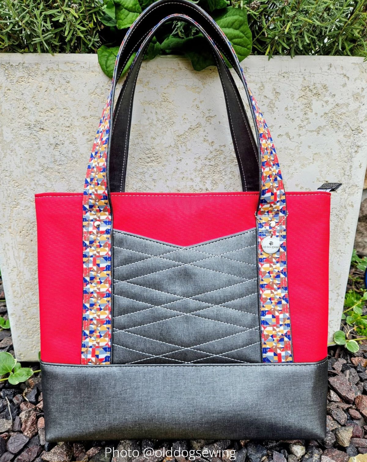 beautiful handmade tote with red top panel, colorful handles, and quilted chevron front pocket.